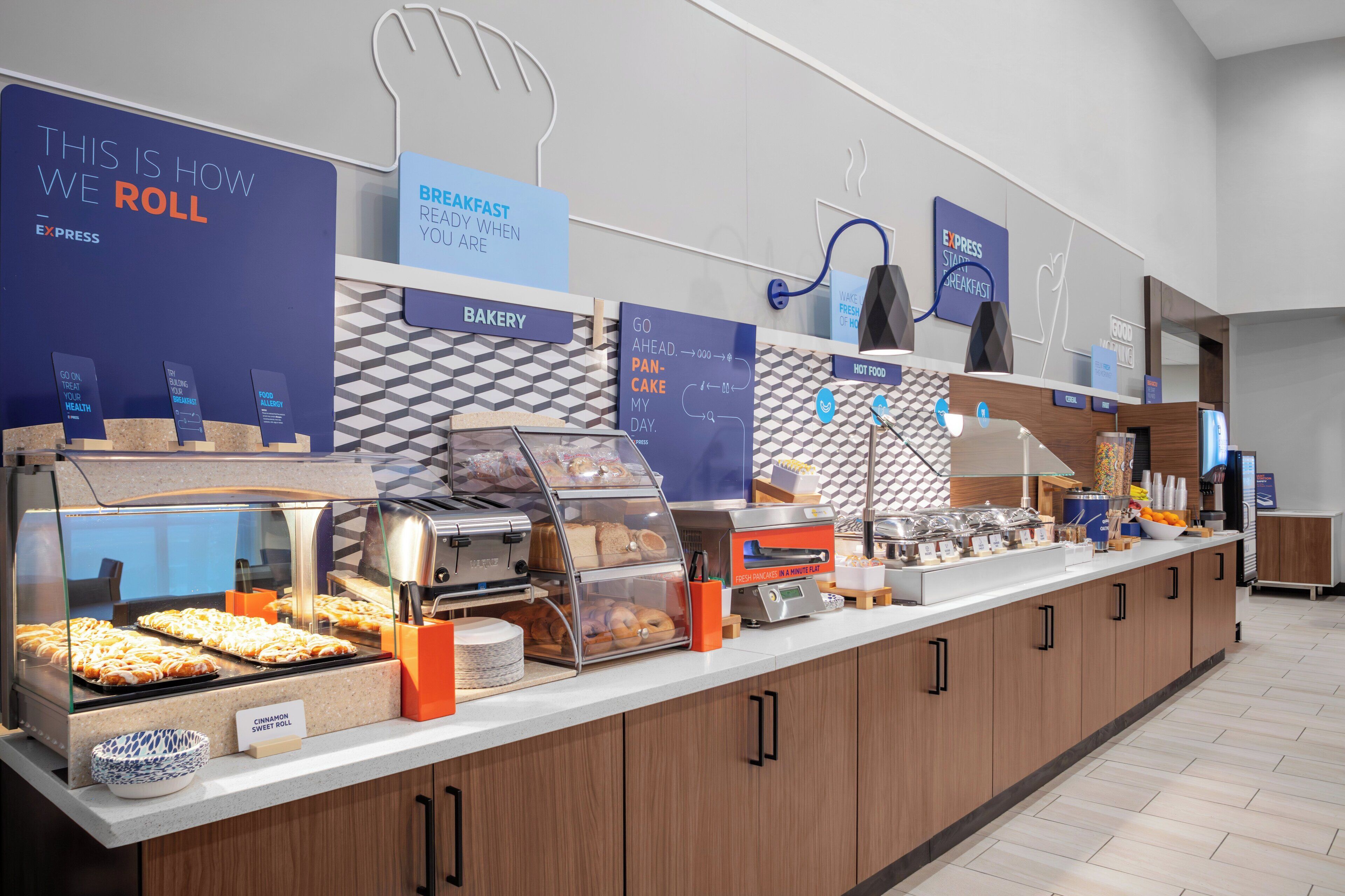 A breakfast buffet area with various food options and clear signage indicating sections like bakery and breakfast.