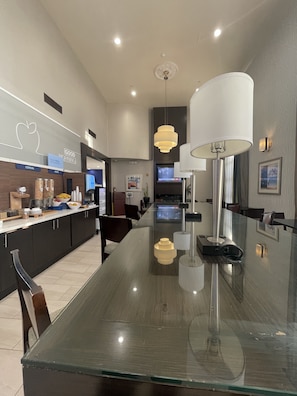 A modern kitchen with a glass dining table, overhead lighting, and a TV. - Holiday Inn Express Hotel & Suites Hermosa Beach by IHG (Hermosa Beach)