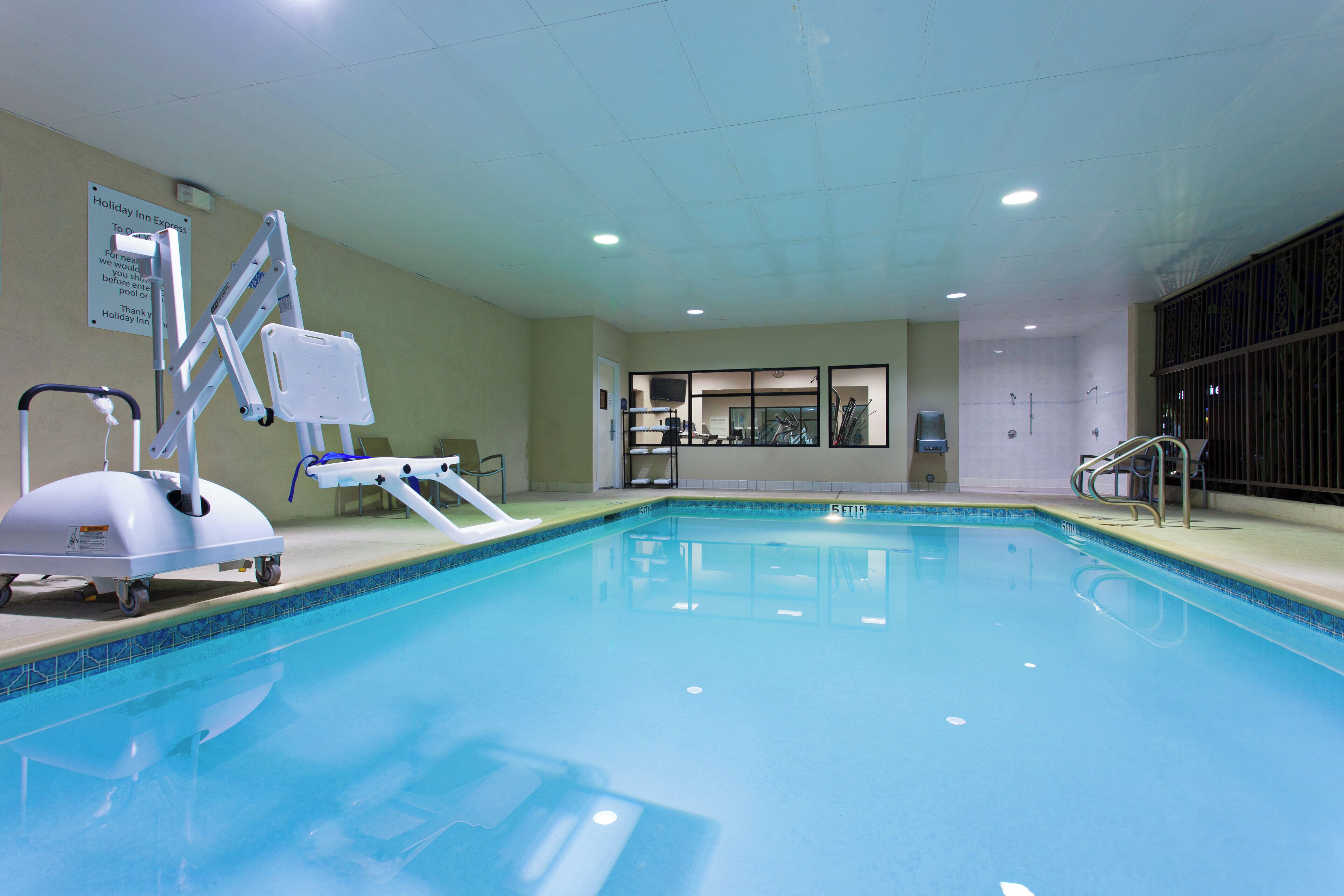 Una piscina interior con elevador, vestuario y zona de duchas.