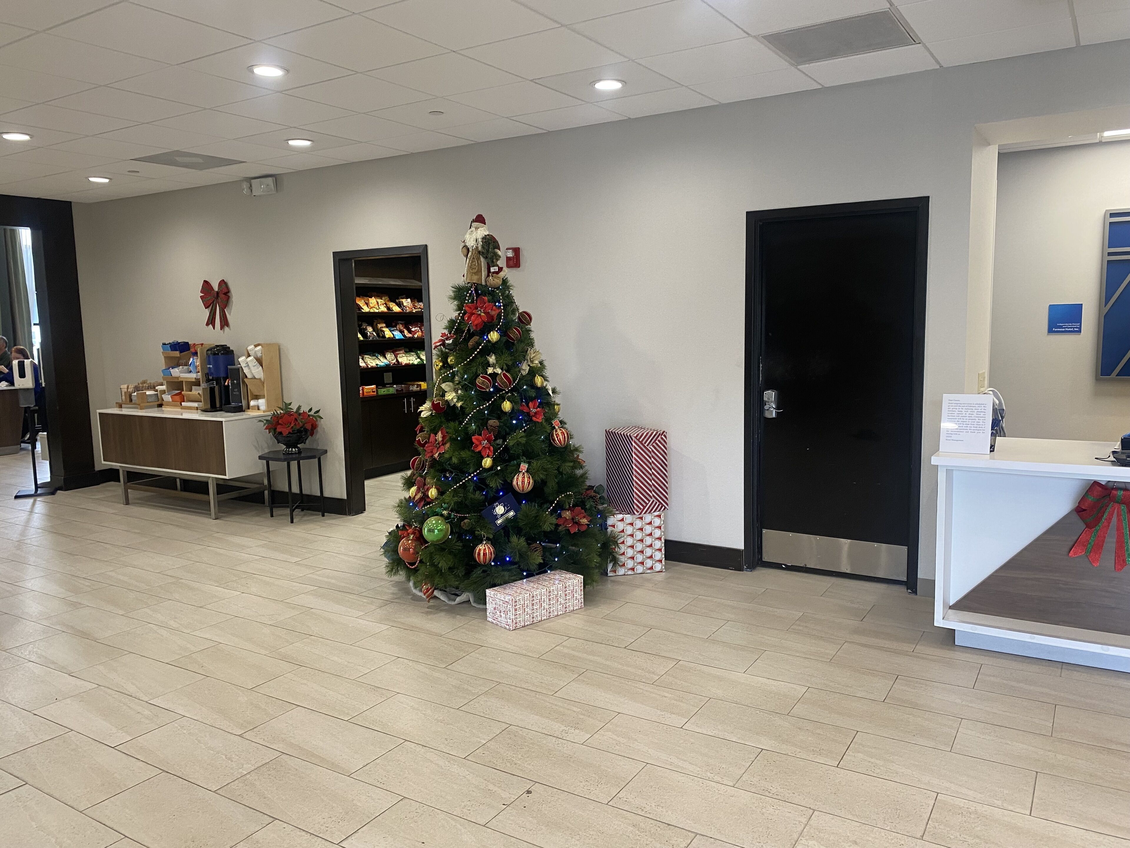 Un espace d’accueil avec un sapin de Noël, un comptoir et une porte.
