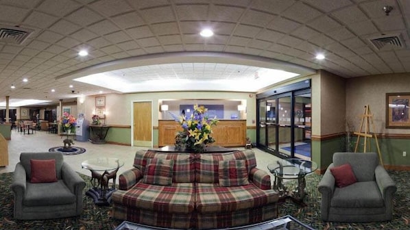 A lobby with a central seating area, a reception desk, and a glass door entrance.