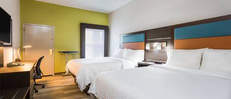 Habitación de hotel con dos camas, un escritorio, una silla y un televisor.