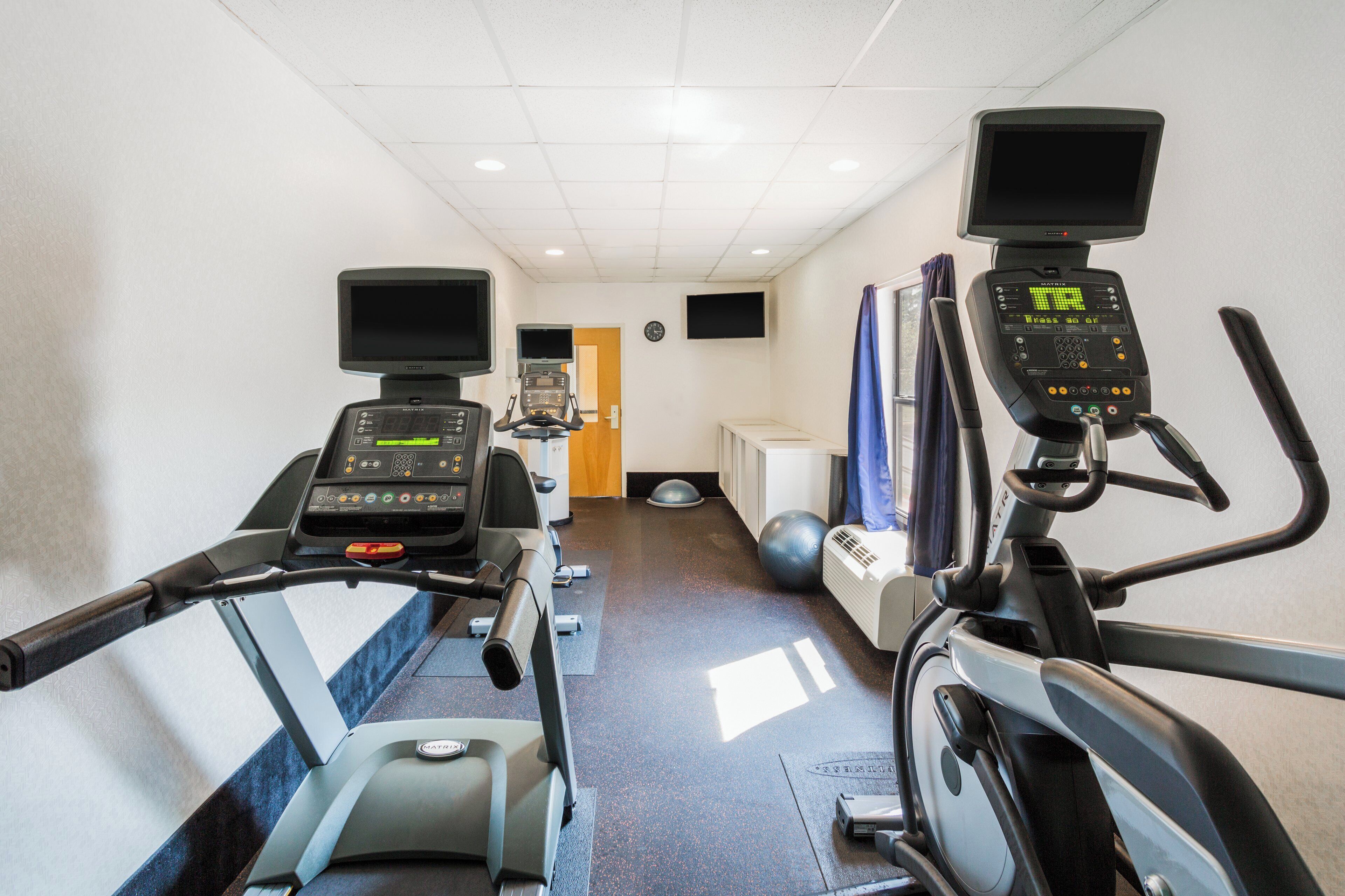 A fitness center with treadmills, a stationary bike, and exercise balls.