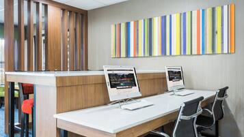 A conference room with two desktop computers, a wooden desk, and a colorful striped wall.