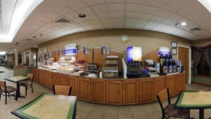 A breakfast bar with various food items and a coffee machine. There are chairs and tables around the bar. - Holiday Inn Express Plymouth by IHG (Plymouth)