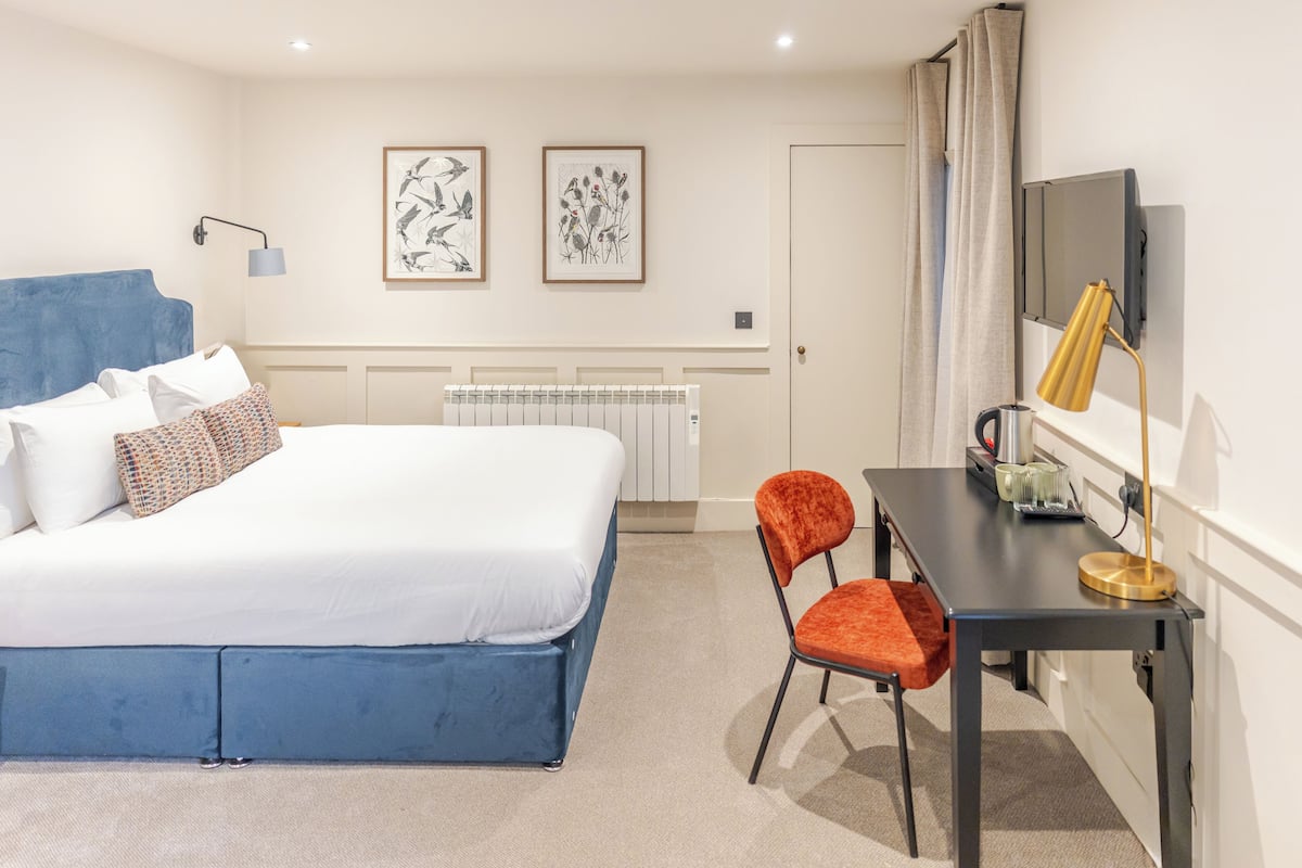 A neatly arranged bedroom with a bed, a desk, and two chairs.