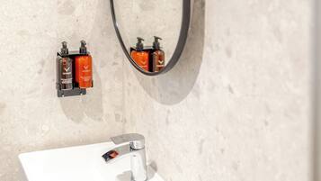 A bathroom with a white sink, a mirror, and two orange soap dispensers mounted on the wall.