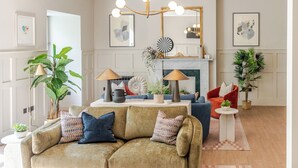 A living room with a sofa, armchairs, a coffee table, a fireplace, and a chandelier.