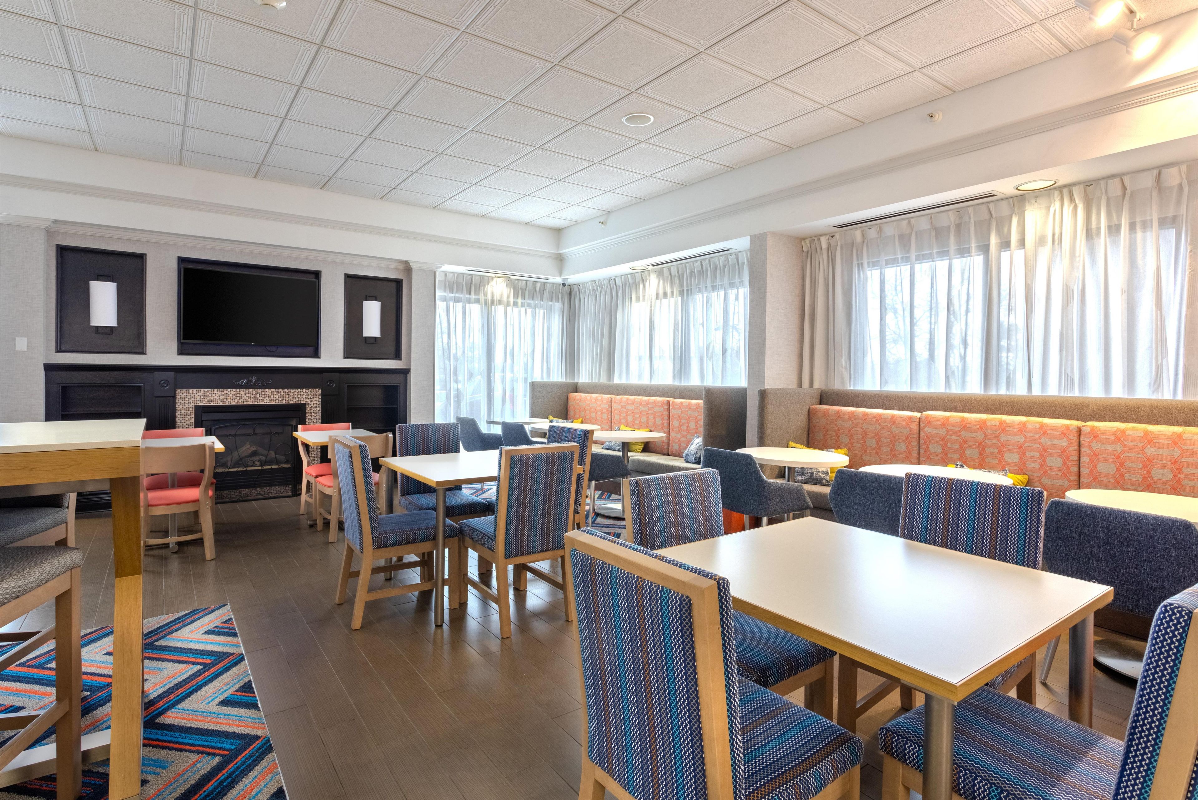 A modern dining area with multiple seating options, including tables and booths, and a fireplace.