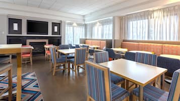 Een moderne eetruimte met verschillende zitmogelijkheden, zoals tafels en ruimtelijke zithoekjes, en een open haard.
