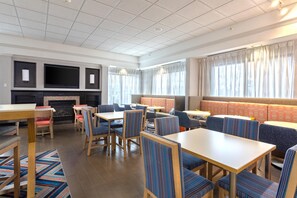 A modern dining area with multiple seating options, including tables and booths, and a fireplace. - Hampton Inn Buffalo South/I-90 (Buffalo)