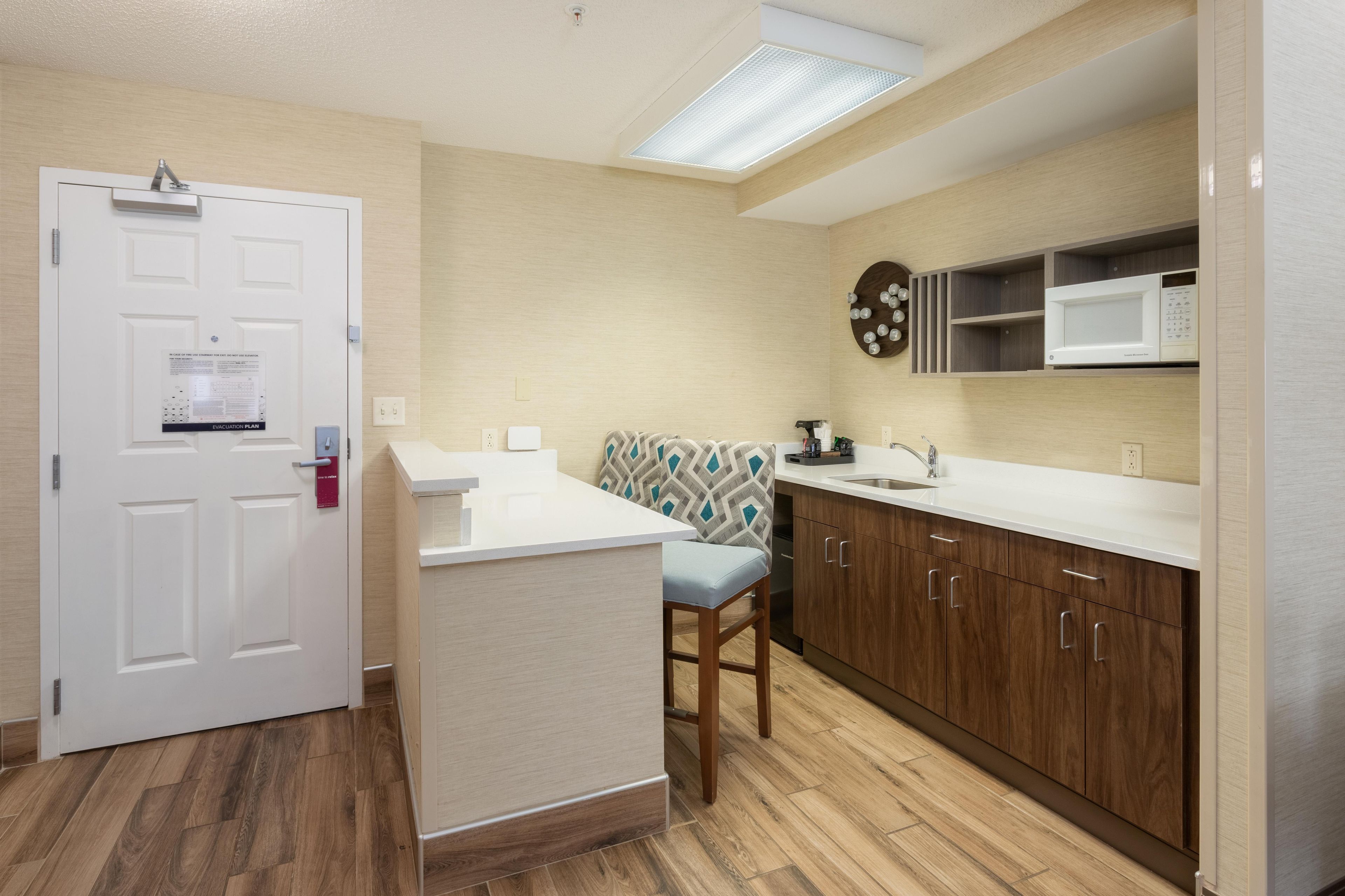 A compact kitchen with a microwave, a sink, and wooden cabinets.