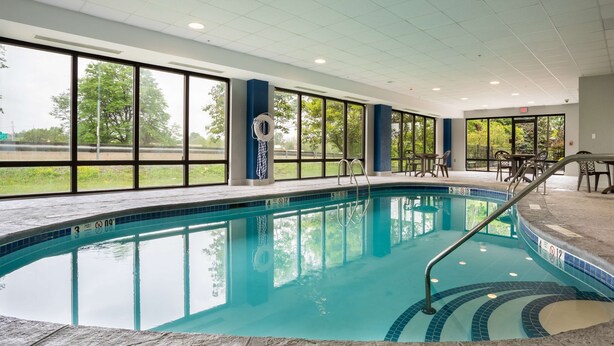 Una piscina interior amb parets de vidre transparent, un terra solat i una cadira de socorrista.