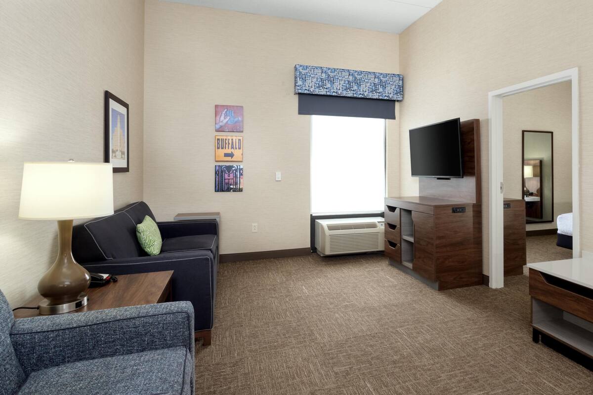 Une chambre d’hôtel avec un canapé, une télévision, un bureau et une fenêtre donnant sur un paysage agréable.