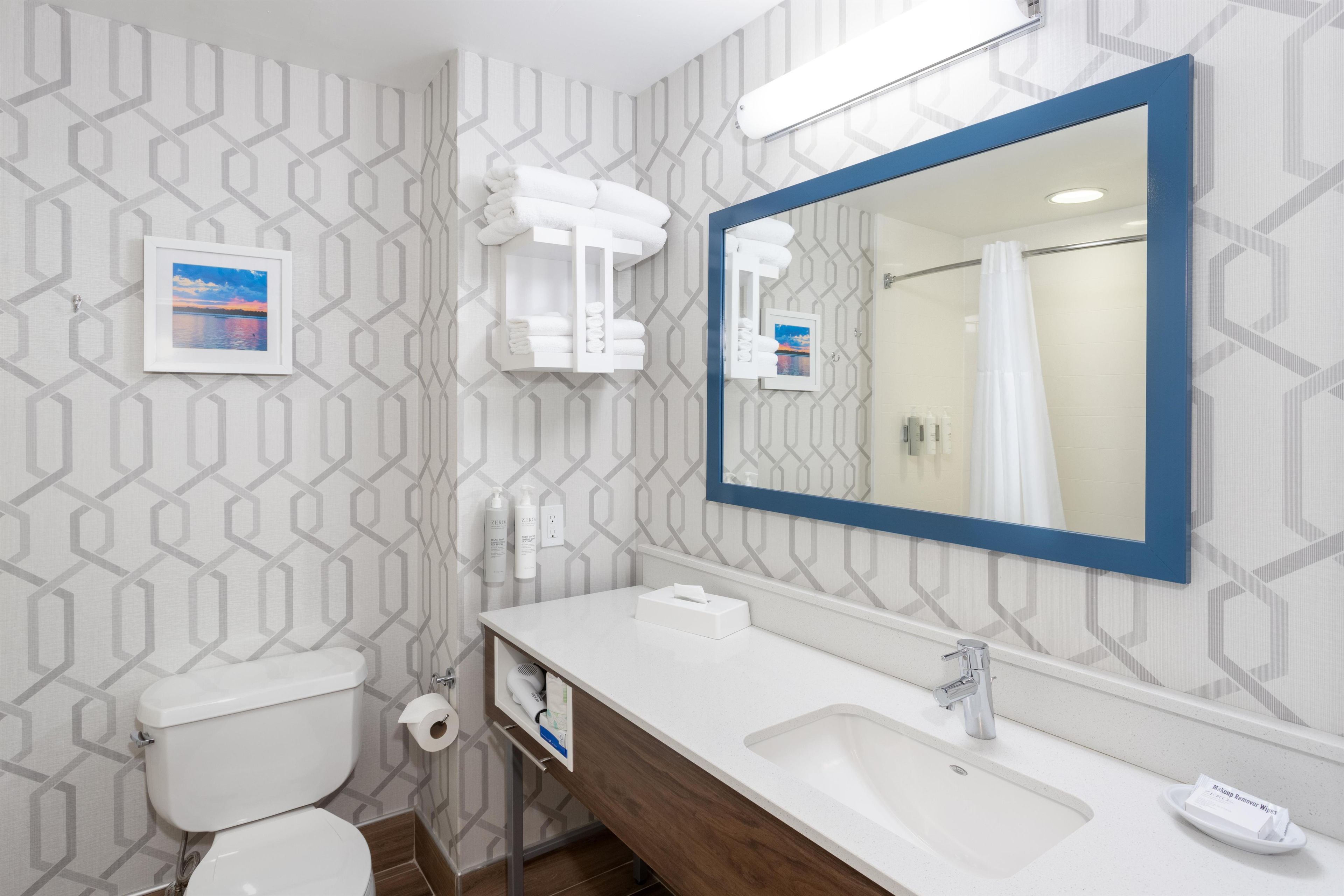 A modern bathroom with a toilet, sink, and mirror.