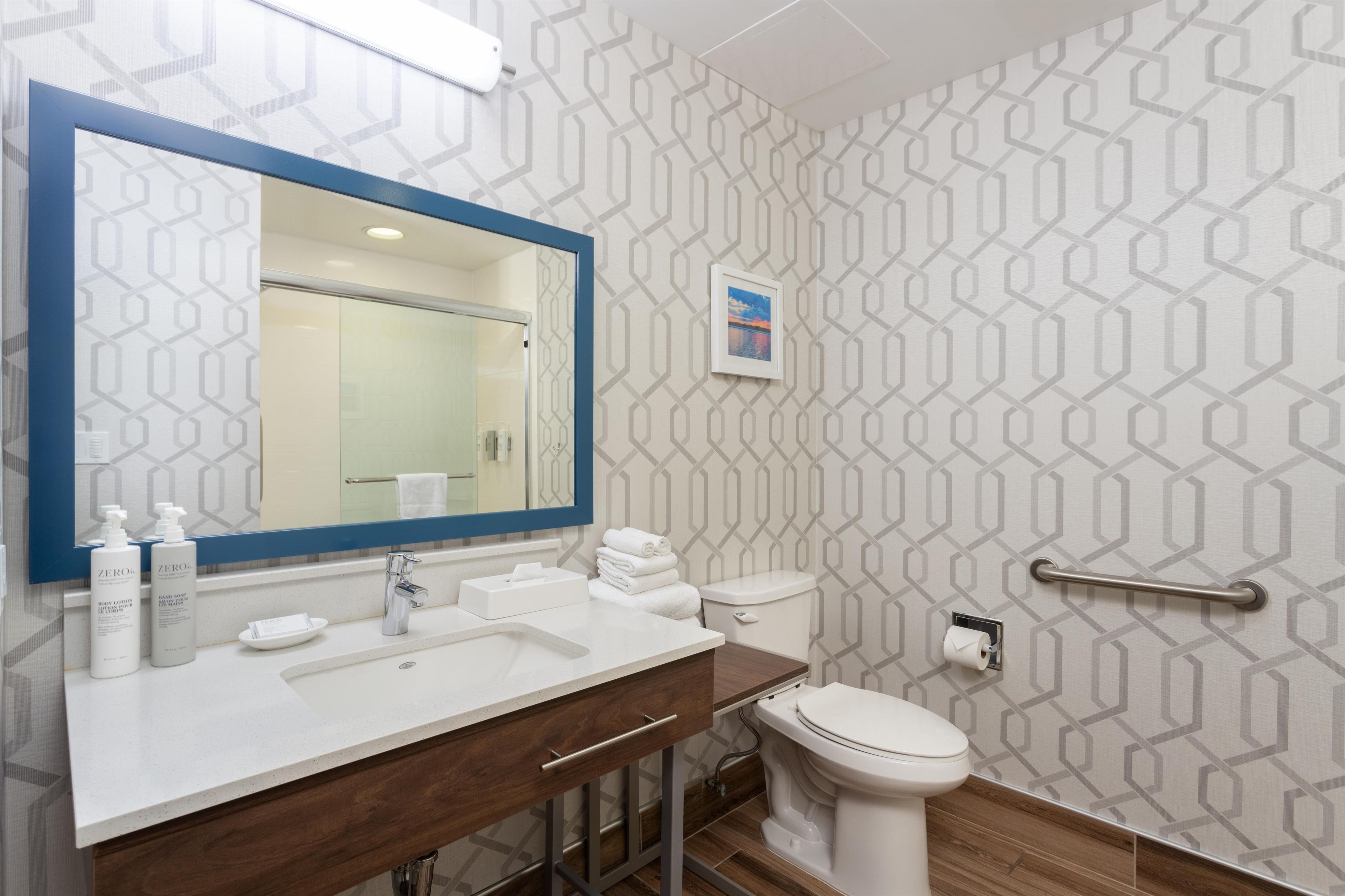 Un baño moderno con un espejo grande, un lavabo, un inodoro y un perchero para toallas.