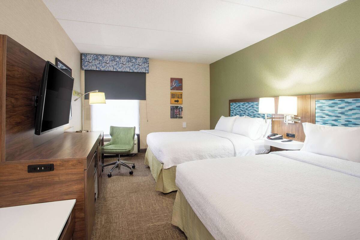 Une chambre d’hôtel avec deux lits, un bureau, une télévision et une chaise.