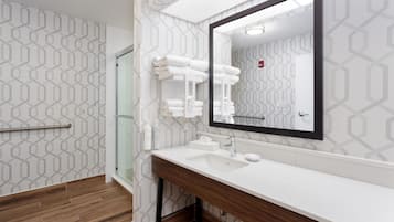 Uma casa de banho moderna com toucador de madeira, um espelho grande e um porta-toalhas.