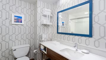 A bathroom with a toilet, sink, mirror, and towel rack.