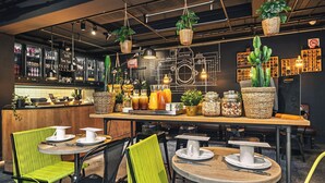 A modern bar area with seating, bar counter, and various plants and decorations. - Zoom Hotel (Brussels)
