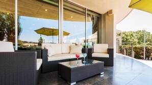 A modern outdoor seating area with a sofa and a coffee table, large windows, and a yellow umbrella. - Hotel Granollers (Granollers)