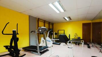 A gym with exercise equipment, a treadmill, and weights.