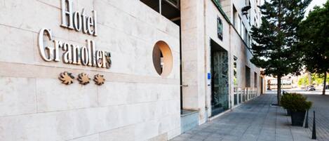 A building with a sign reading "Hotel Granollers" and a tiled sidewalk.