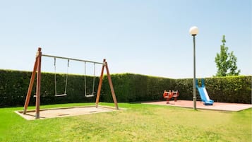 Enjoy a fun-filled day in this play area with a swing set, slide, and play structure surrounded by lush hedges.