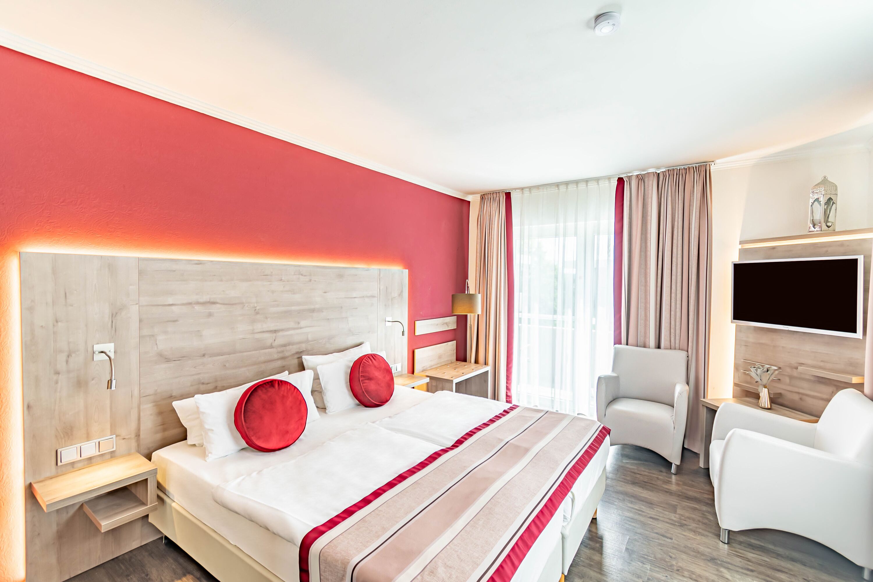 A hotel room with a large bed, a TV, a desk, and a chair.