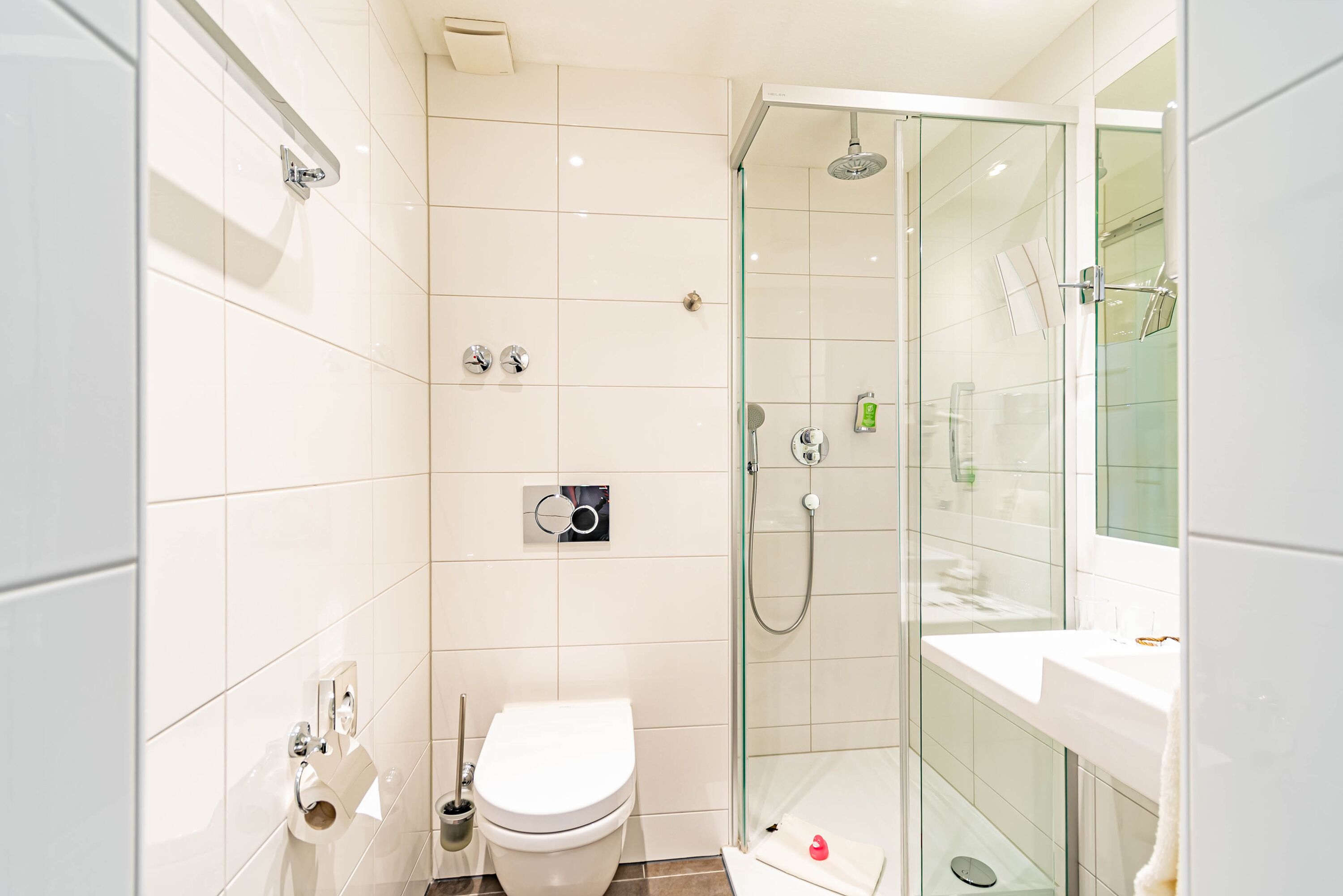 A modern bathroom with a glass-enclosed shower, a toilet, and a sink.