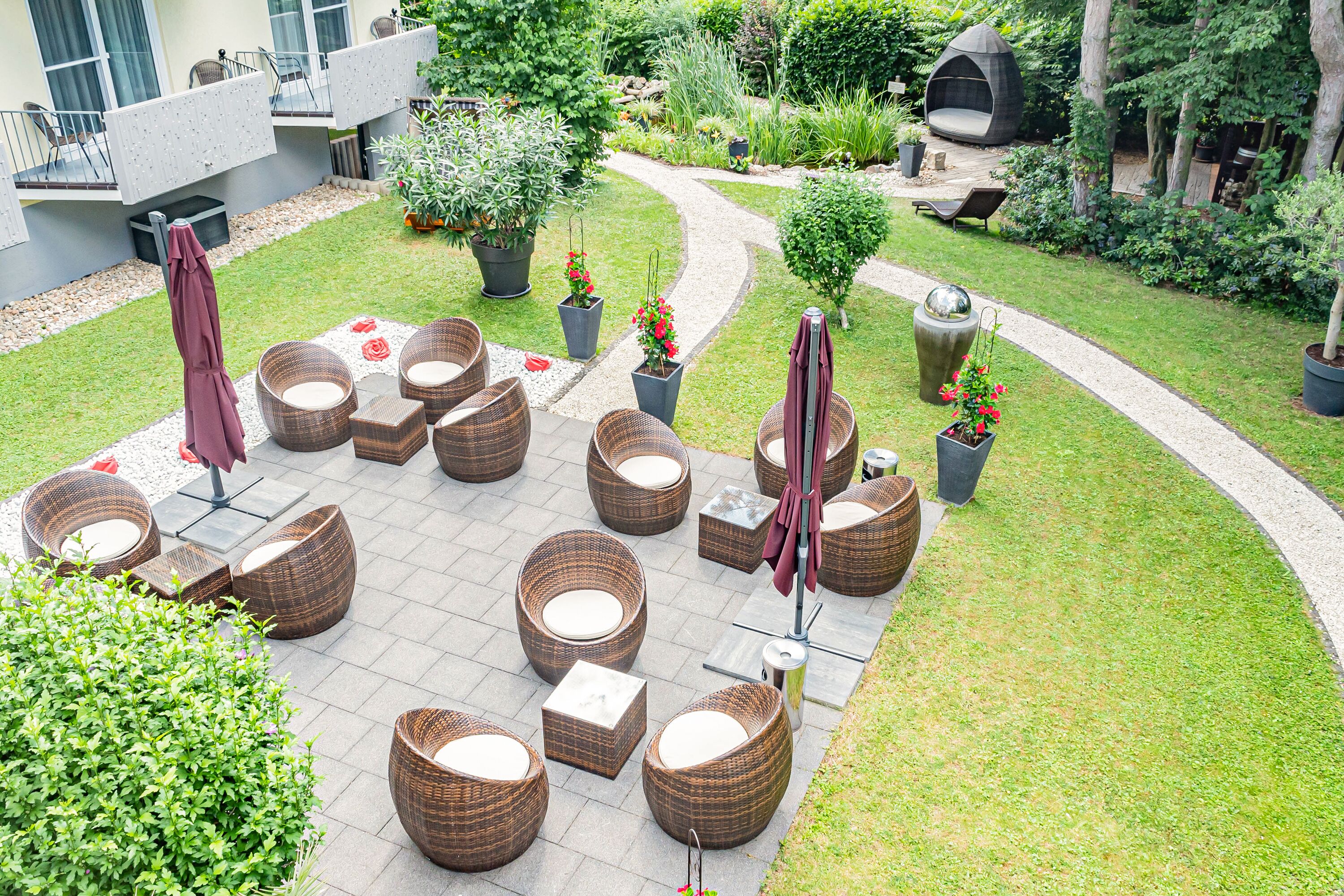 Une cour avec des espaces de repos en plein air, des plantes en pot et un chemin.