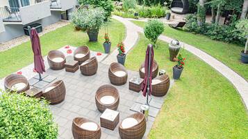 Une cour avec des espaces de repos en plein air, des plantes en pot et un chemin.