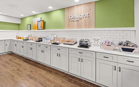 A modern kitchen with white cabinets, a green accent wall, and various breakfast items displayed on the counter.