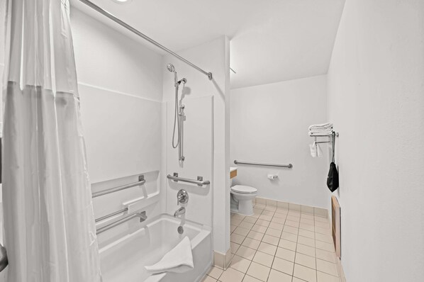 A bathroom with a shower, toilet, and grab bars. - Spark by Hilton Sterling Dulles Airport (Sterling)
