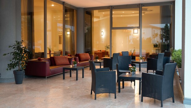 A modern indoor seating area with sofas, chairs, and tables, featuring large glass windows and a potted plant. - Best Western Hotel Fiera Verona (Verona)