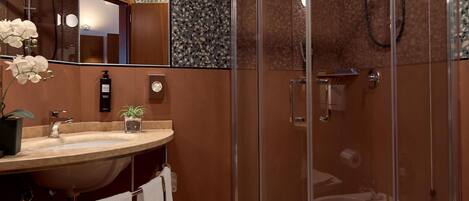 A modern bathroom with a glass-enclosed shower, a marble sink, and a large mirror.