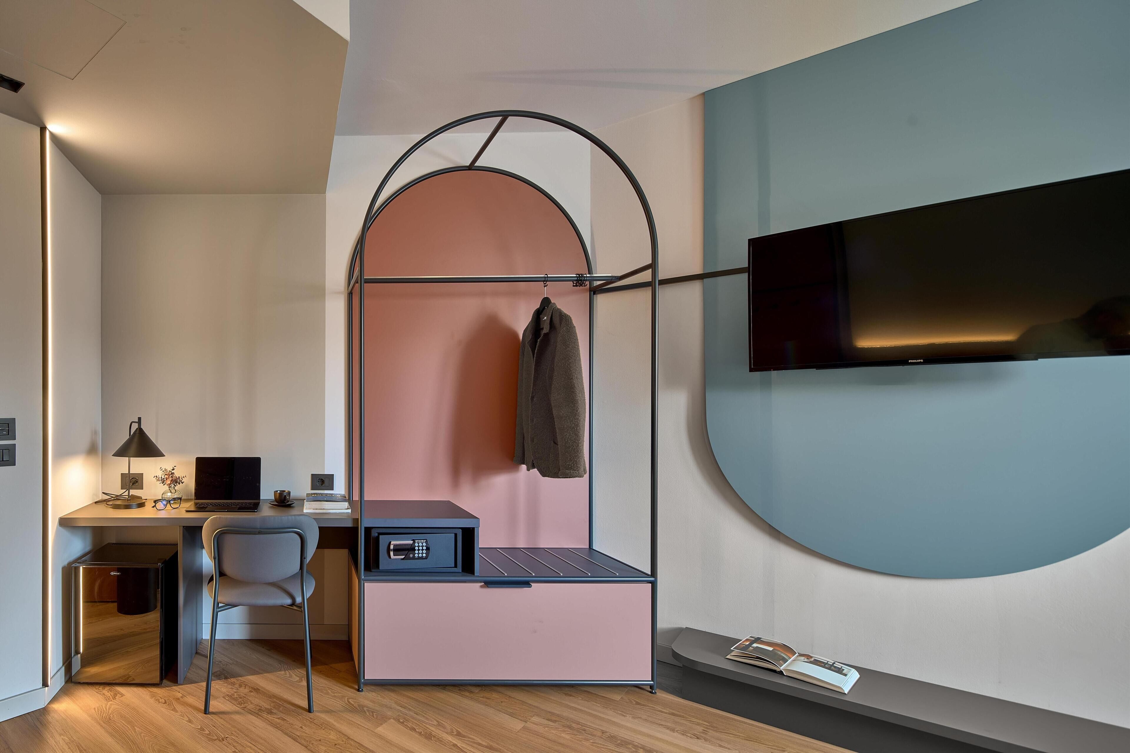 Une pièce de taille modeste, équipée d’un bureau, d’une chaise et d’un téléviseur fixé au mur.