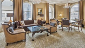 A spacious living room with a large sofa, armchairs, a coffee table, and a dining area with a chandelier. - Omni San Francisco Hotel (San Francisco)