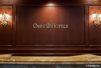 A bar area with a central island, bar stools, and shelves stocked with bottles. at Omni San Francisco Hotel