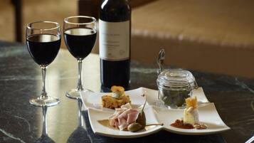 Una mesa con dos copas de vino, una botella, un plato con comida y un tarro.