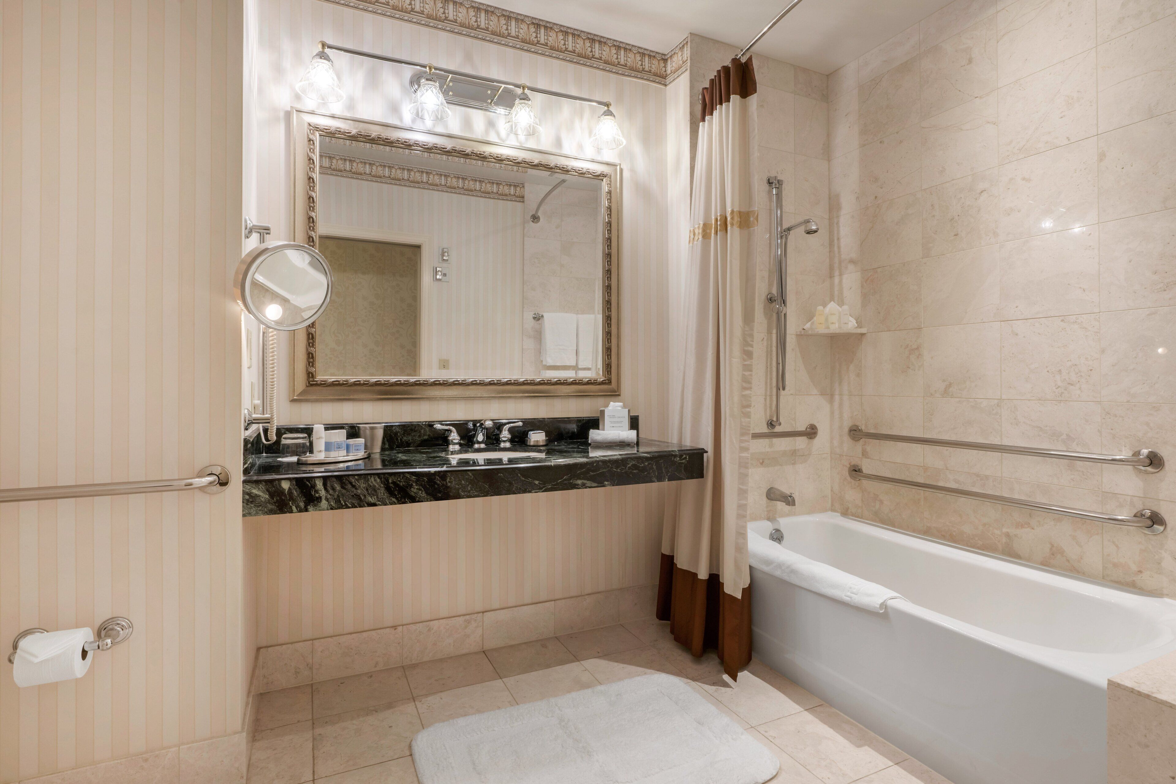 Ein modernes Badezimmer mit einem großen Spiegel, einer Badewanne und einem Waschtisch mit Marmorplatte.