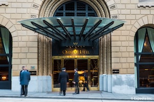 De ingang van Hotel Omni met een klassiek architectuurontwerp, waaronder een groot rondboogvenster en een luifel boven de entree.