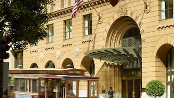 A historic building with a prominent American flag, a tram, and a well-maintained garden.
