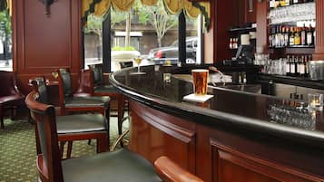 A bar area with wooden chairs, a curved bar counter, and a view of the street outside.