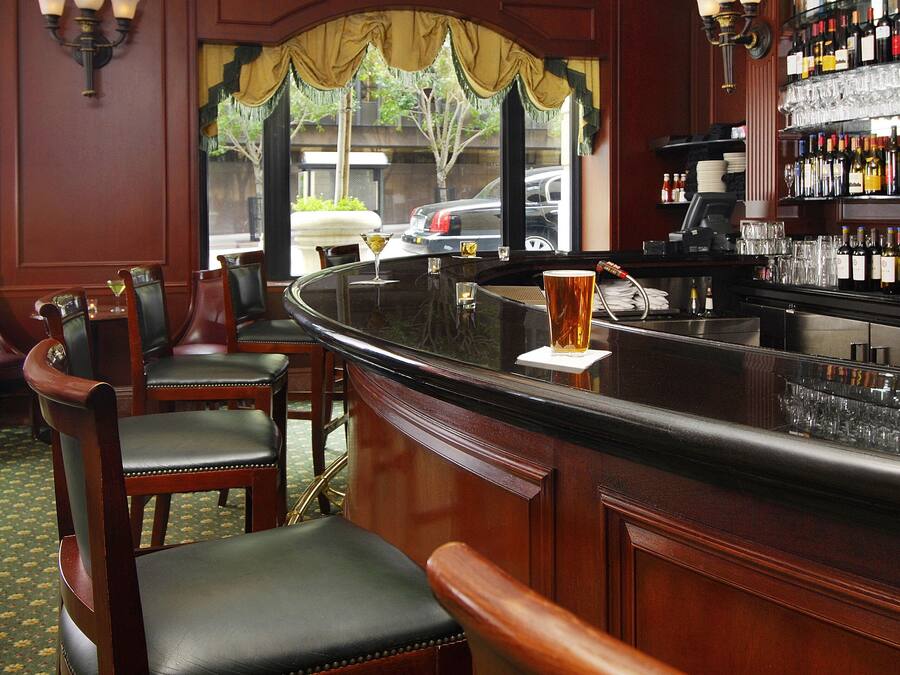 A bar area with wooden chairs, a curved bar counter, and a view of the street outside.