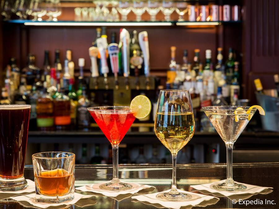 Un bar avec différents verres remplis de boissons et, au fond, une sélection de bouteilles.