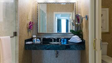 A bathroom with a marble sink, a large mirror, and a toilet visible through an open door.