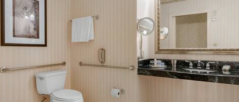A bathroom with a toilet, a sink, a mirror, and a towel rack.