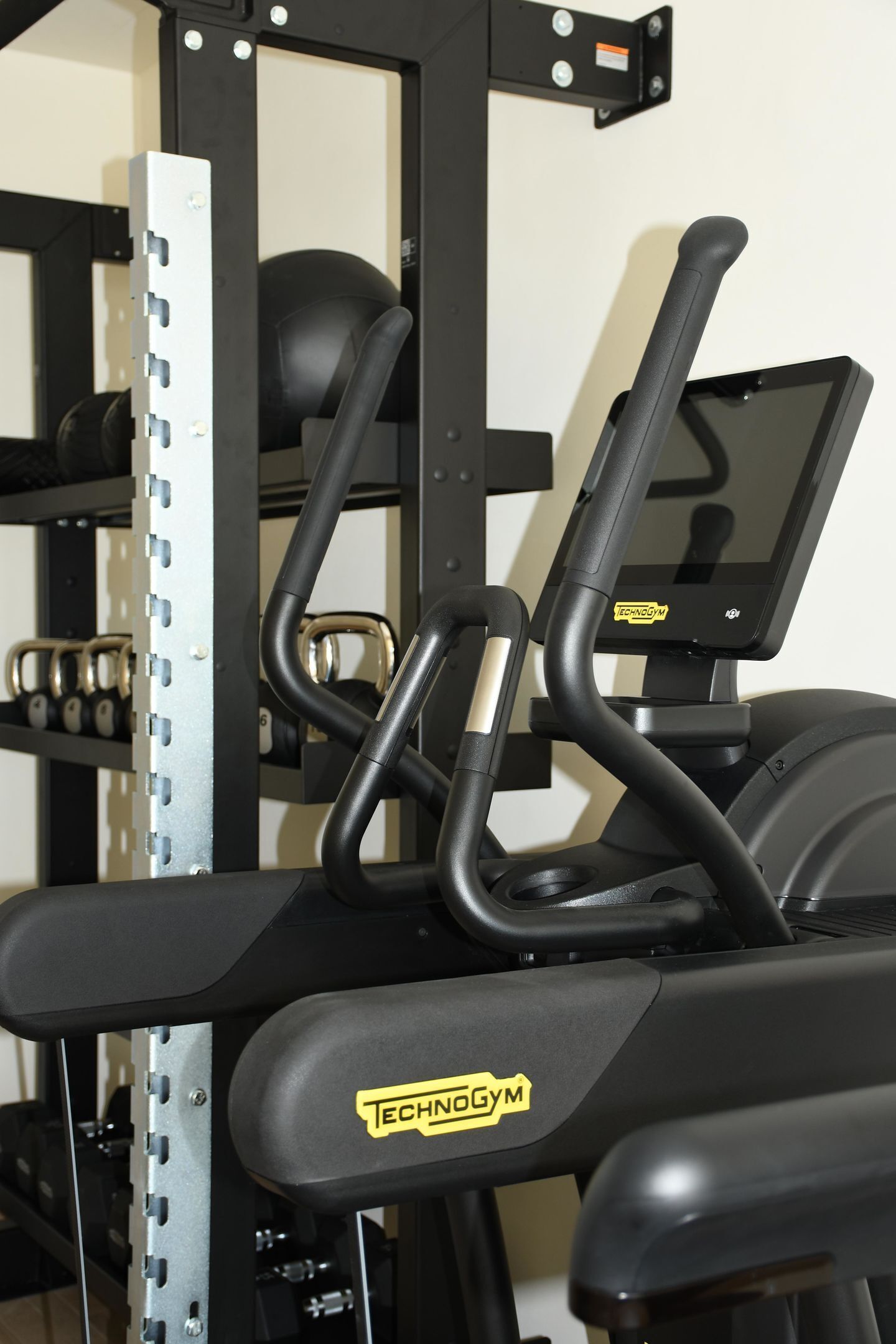 Un gimnasio con cinta de correr, máquinas de pesas y una pantalla digital.