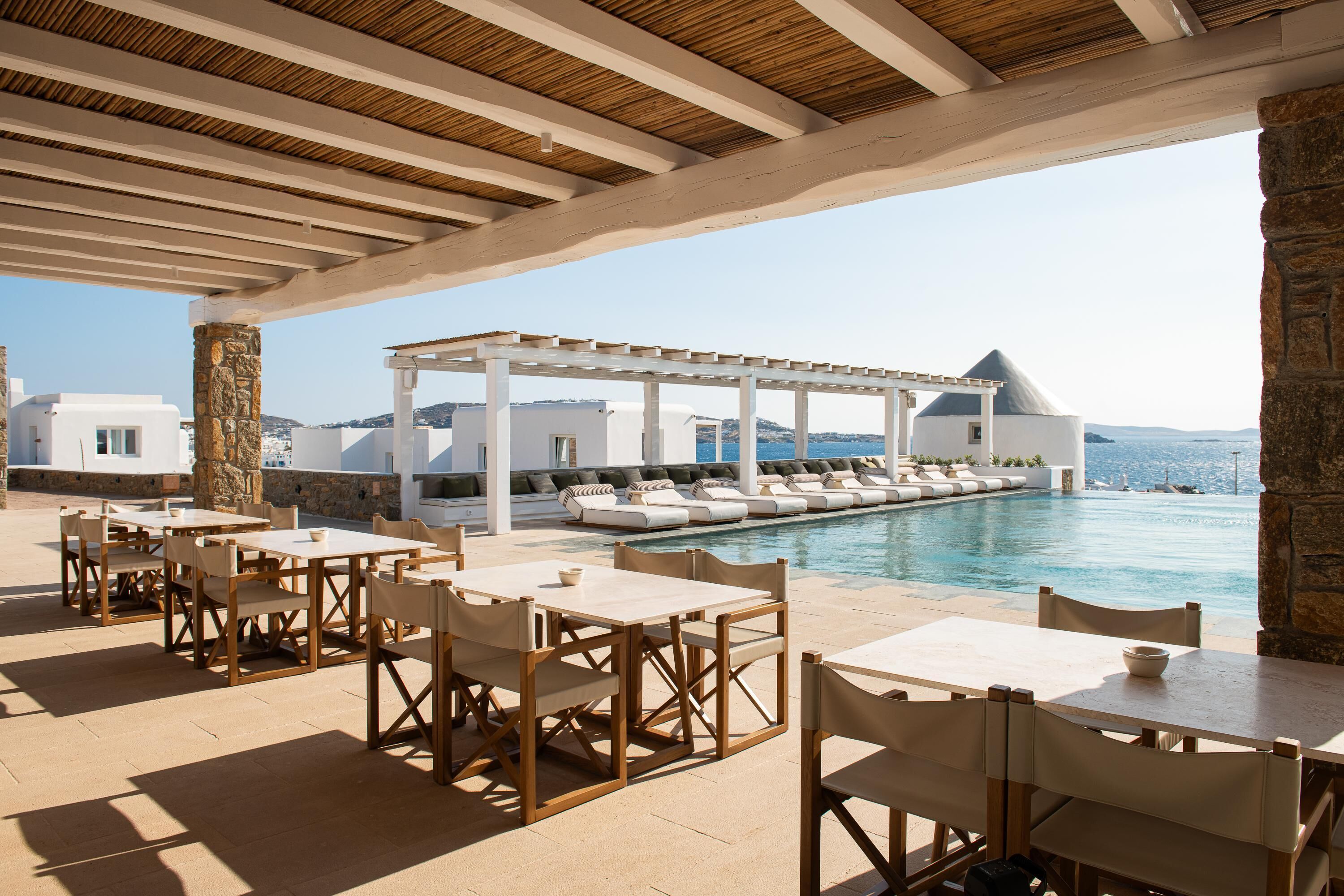 A poolside area with outdoor seating and a view of the sea.